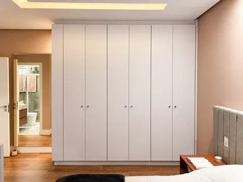 Dormitórios - Solteiro e Infantil &mdash; Suíte Master com Roupeiro Branco Piso ao Teto e Cabeceira Estofada